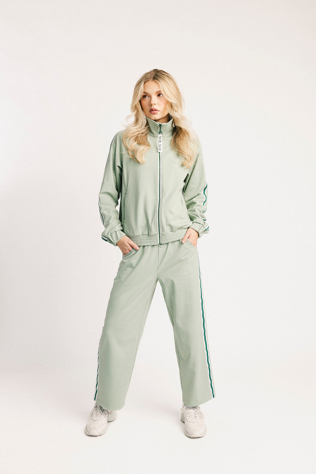 Person wearing a light green tracksuit on a white background