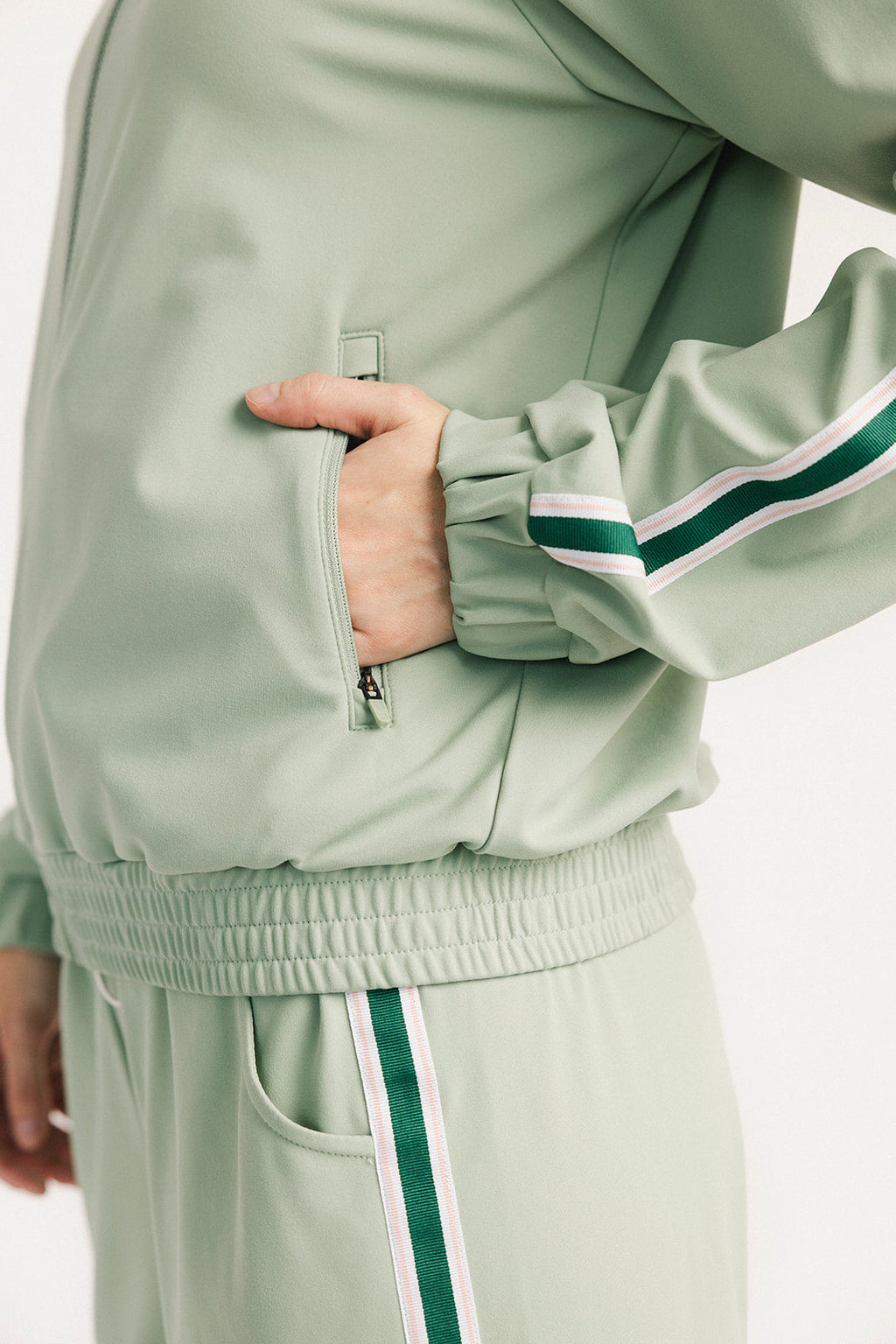 Light green tracksuit with white and green stripes on a plain background